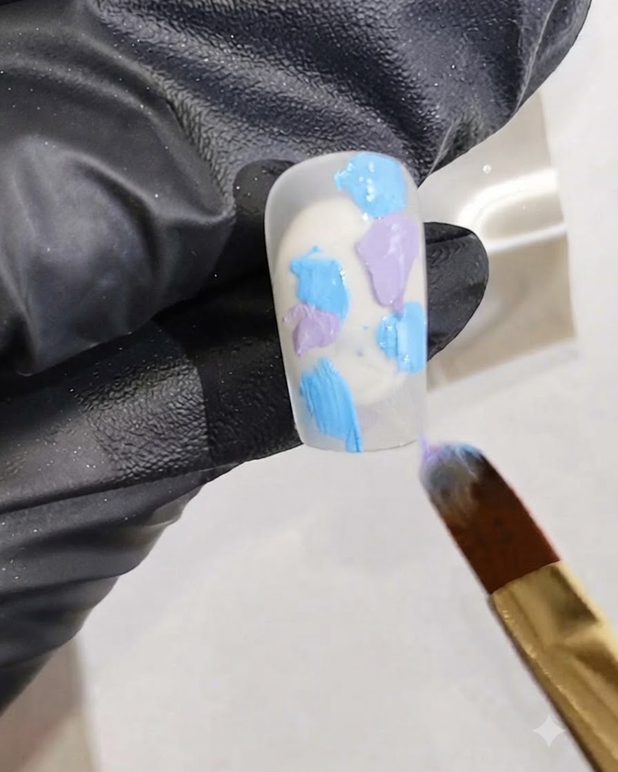 Un pinceau fin ajoutant des traînées de gel rose vif dans le mélange de gel humide sur un ongle.