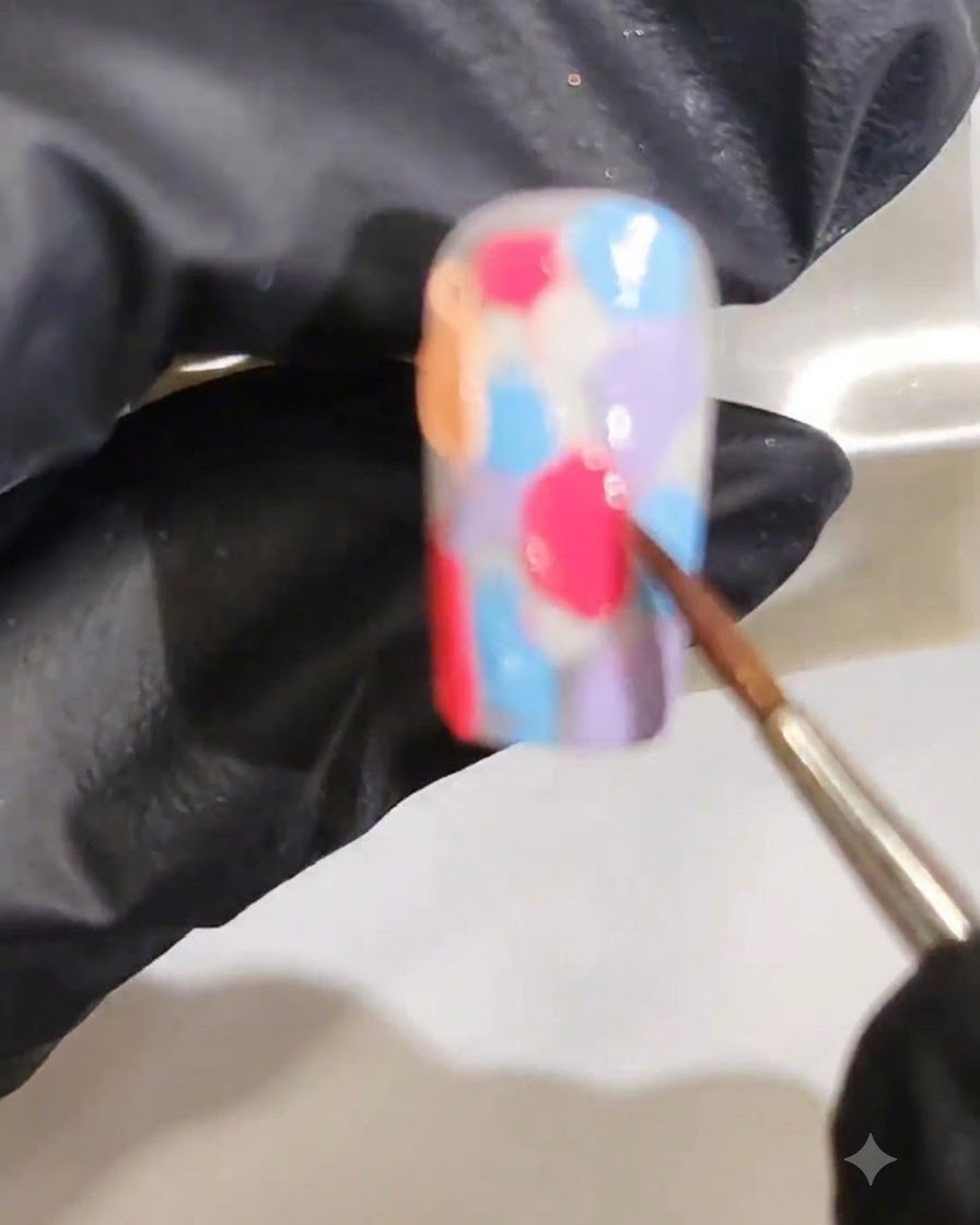 Un pinceau fin mélangeant plusieurs couleurs de gel humide pour former un dégradé marbré aquarelle fluide.