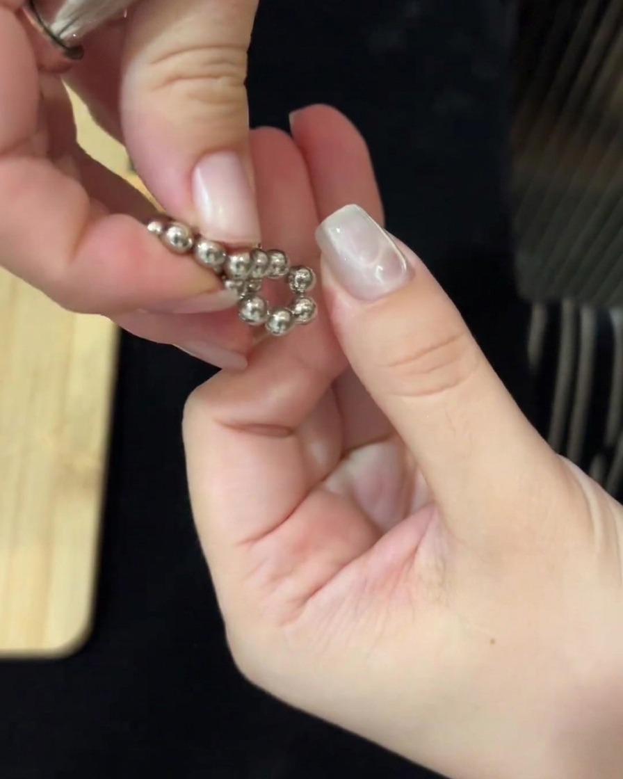 Des mains utilisant des aimants des deux côtés pour manipuler des billes métalliques et créer des vagues deau sur longle.