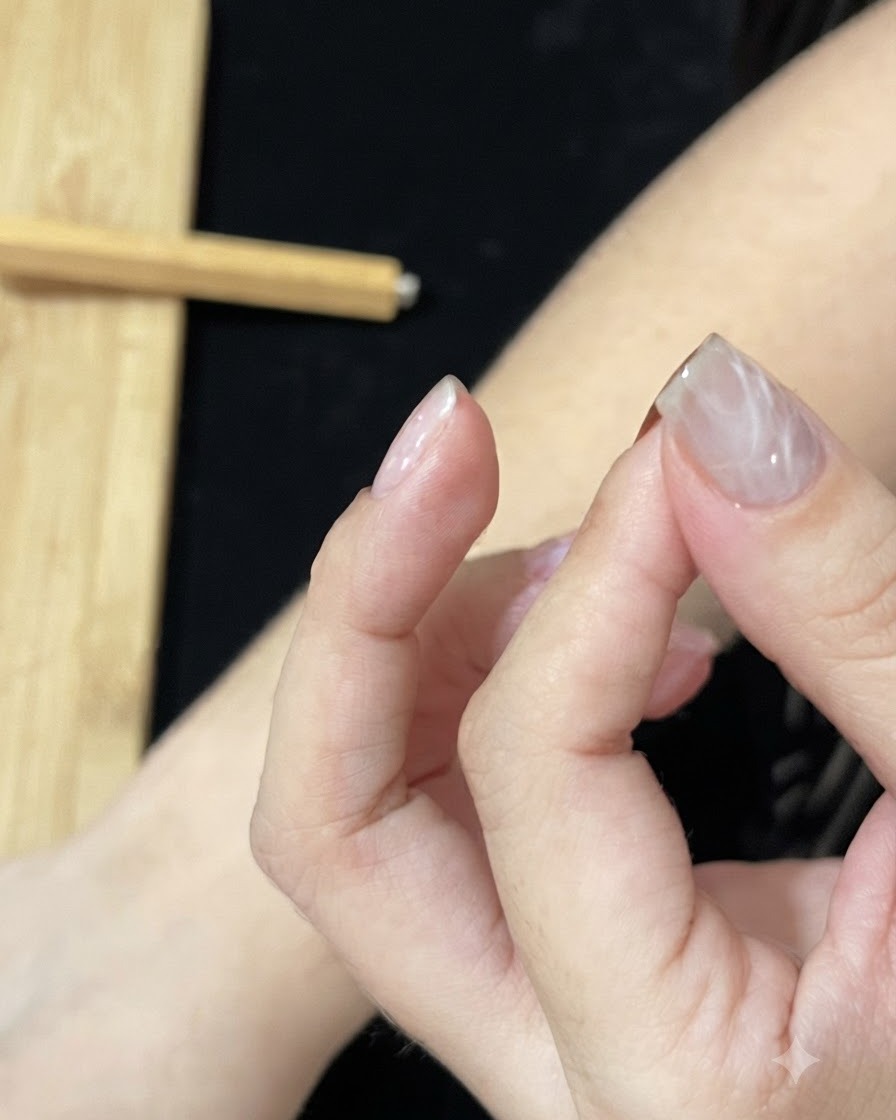Une main positionnée sous une lampe à ongles UV ou LED pour catalyser la couche de gel texturée.