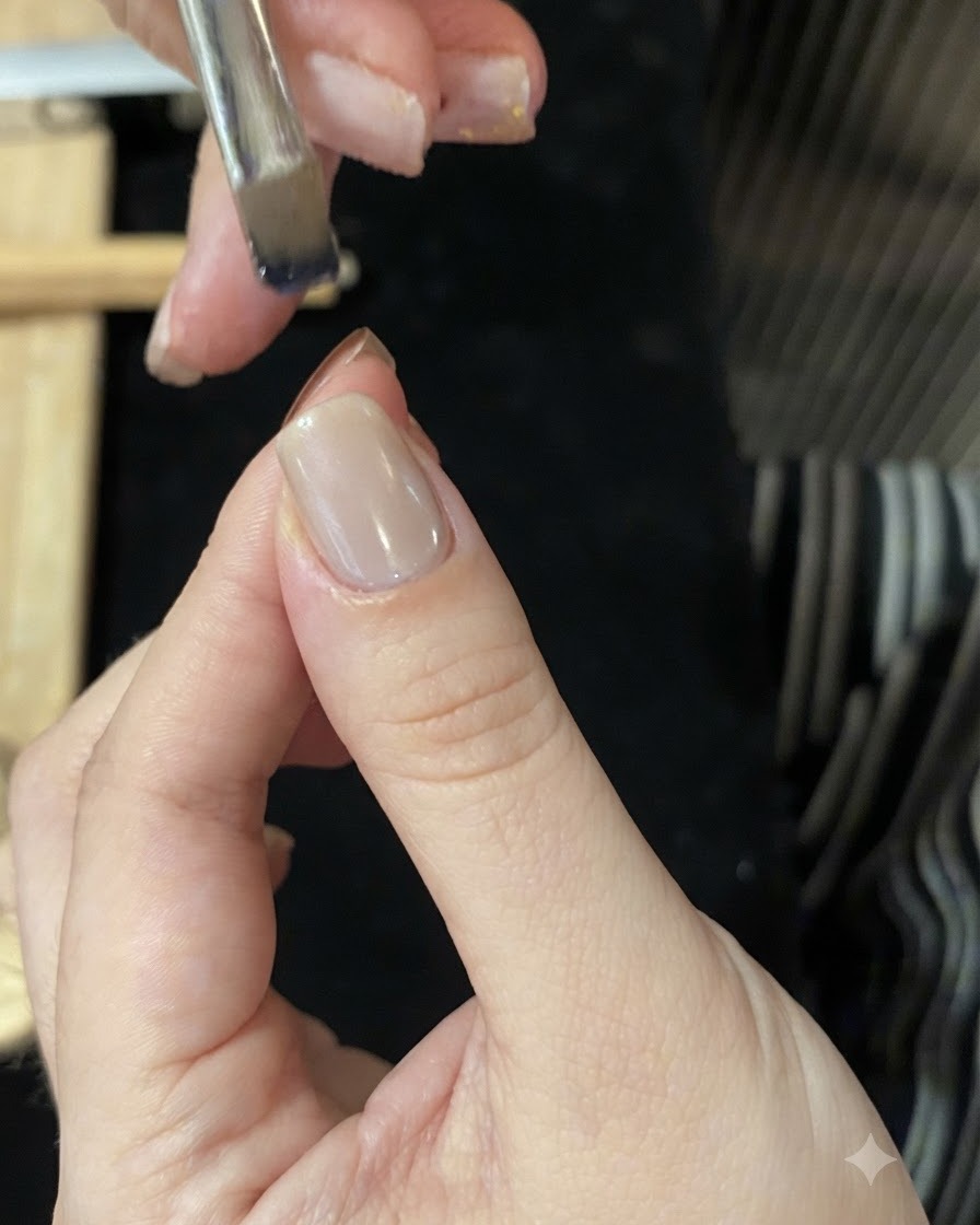 Un pinceau chargé de gel verrier bleu tenu au-dessus de la pointe dun ongle pour créer un dégradé ombré.