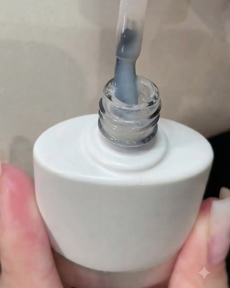 Un pinceau sortant dun flacon de vernis gel blanc avec un revêtement blanc laiteux visible sur les poils.