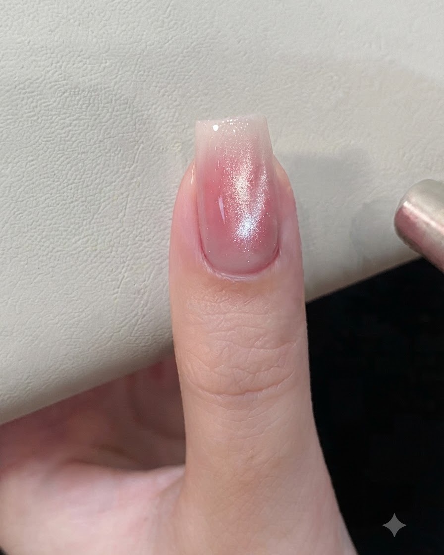 Un outil aimanté tenu près dun ongle en gel œil-de-chat rose et argenté pour façonner les particules magnétiques.