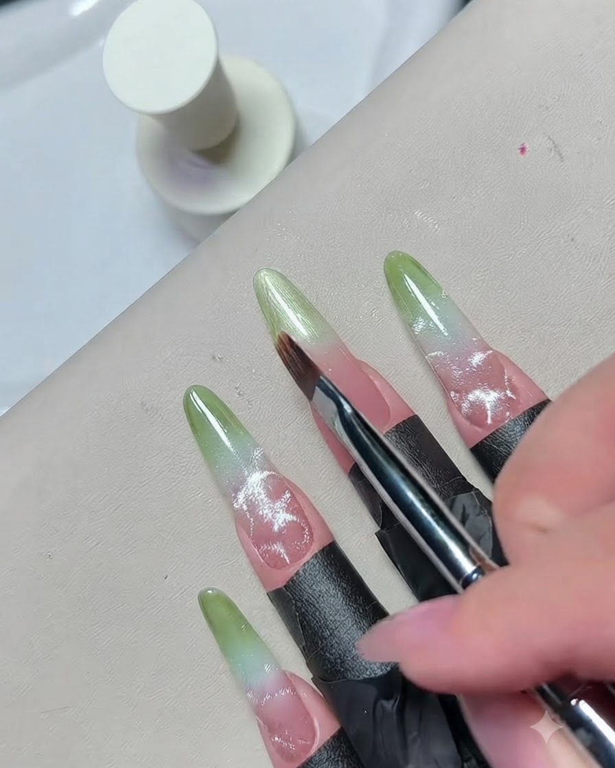 Gros plan dun pinceau fin estompant le bord du vernis gel vert pour créer un fondu en dégradé homogène.