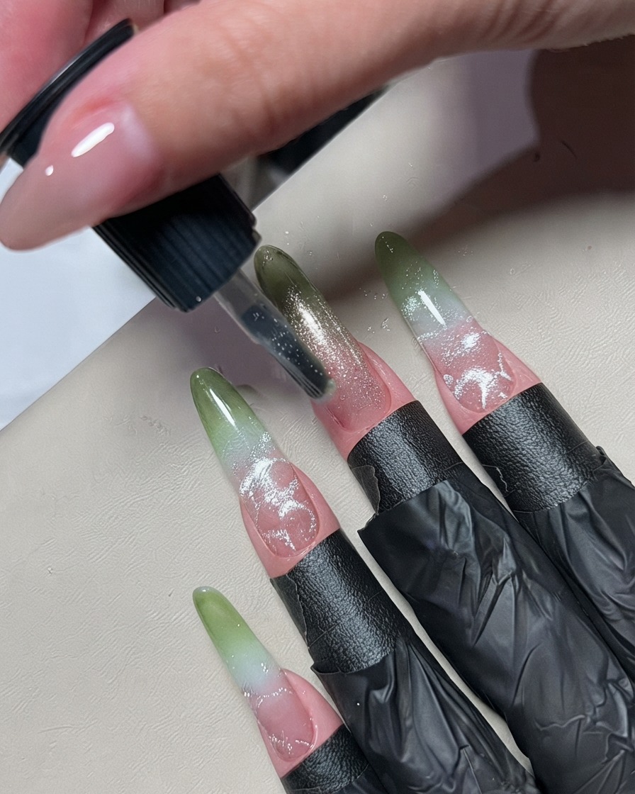 Un petit pinceau de nail art appliquant une fine ligne de vernis gel métallique argenté au centre dun ongle en ombré.