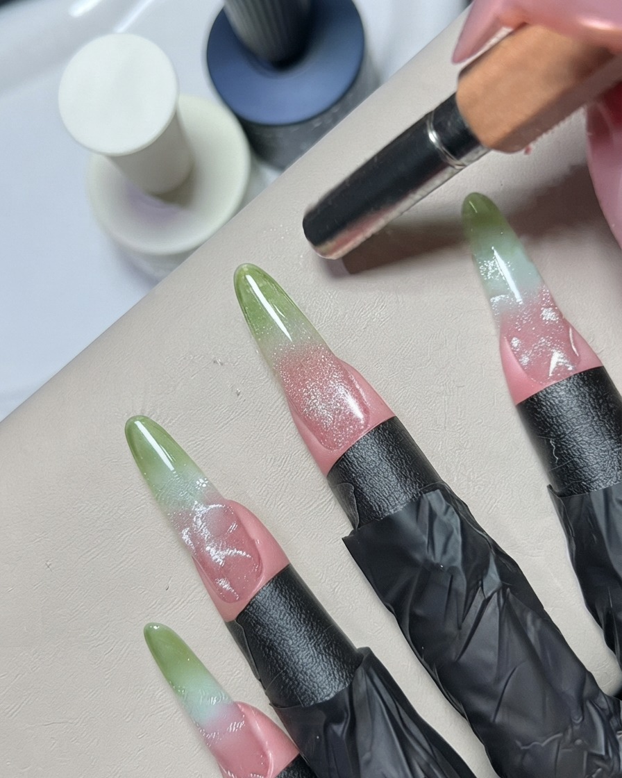 Un outil de dotting ou un pinceau de détail en métal estompant les détails en gel argenté sur un ongle décoré.
