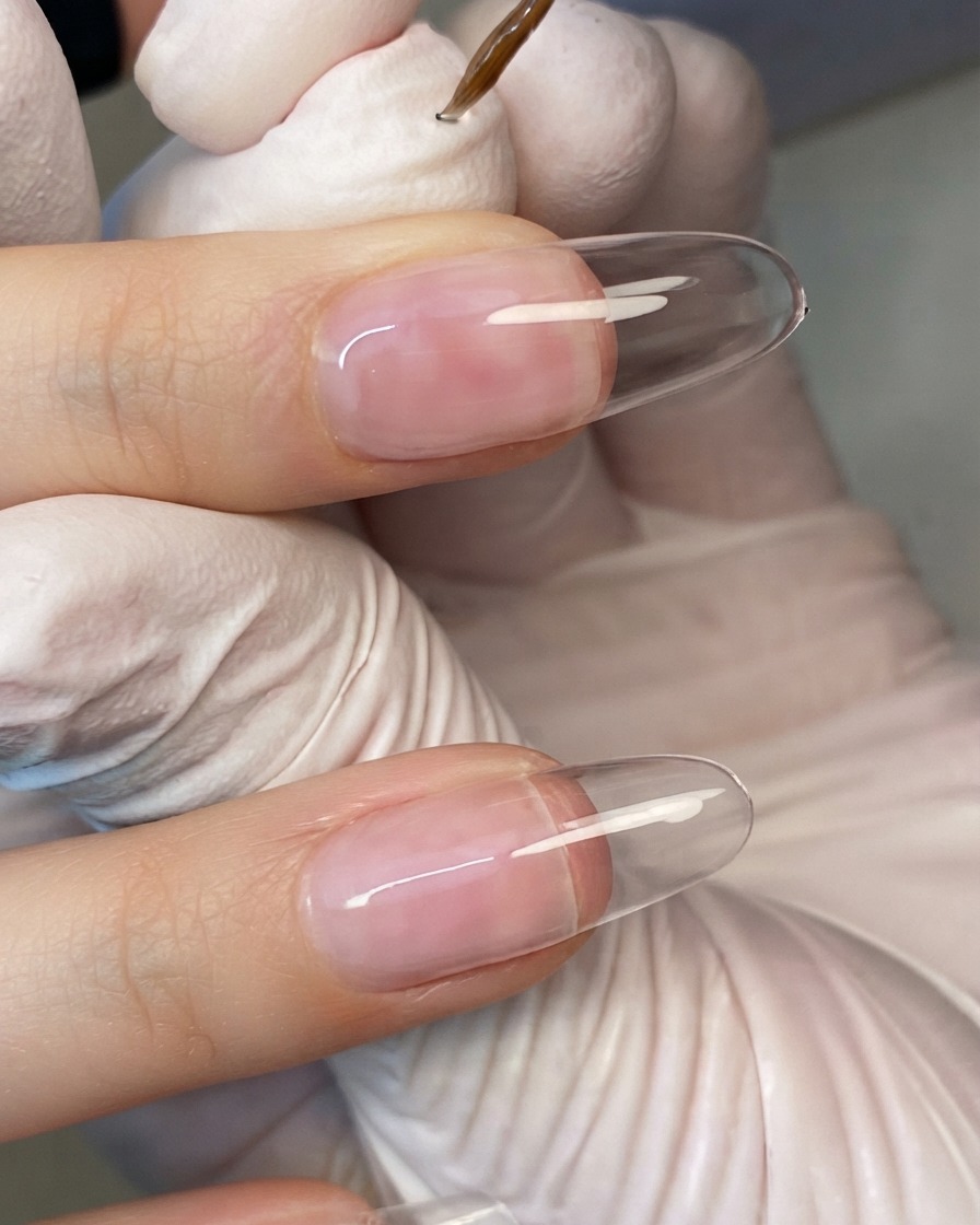 Une main positionnée sous une lampe à ongles UV compacte avec les doigts éclairés par la lumière LED.