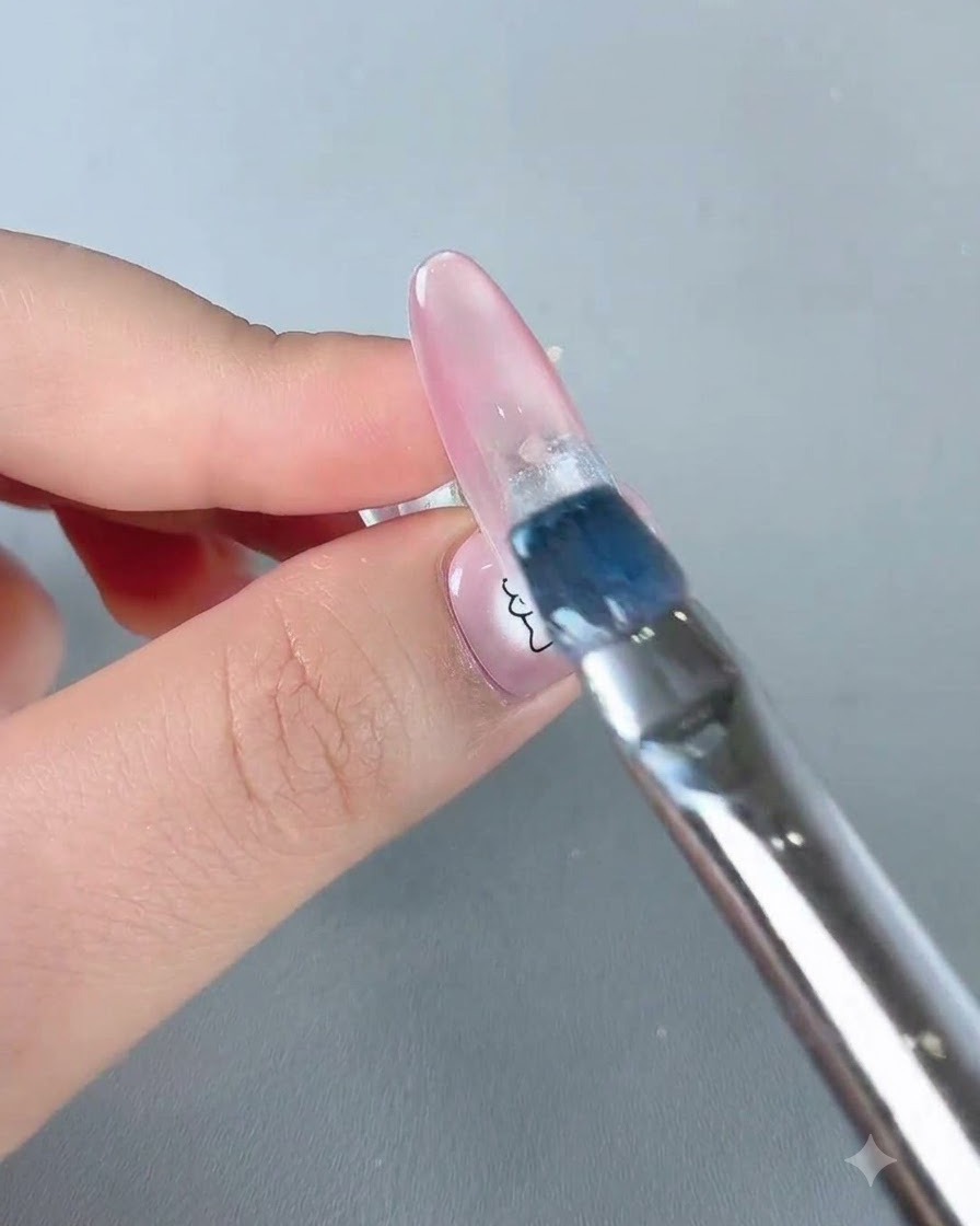 Un pinceau appliquant une touche de vernis gel bleu ciel près de la zone de la cuticule dun ongle.