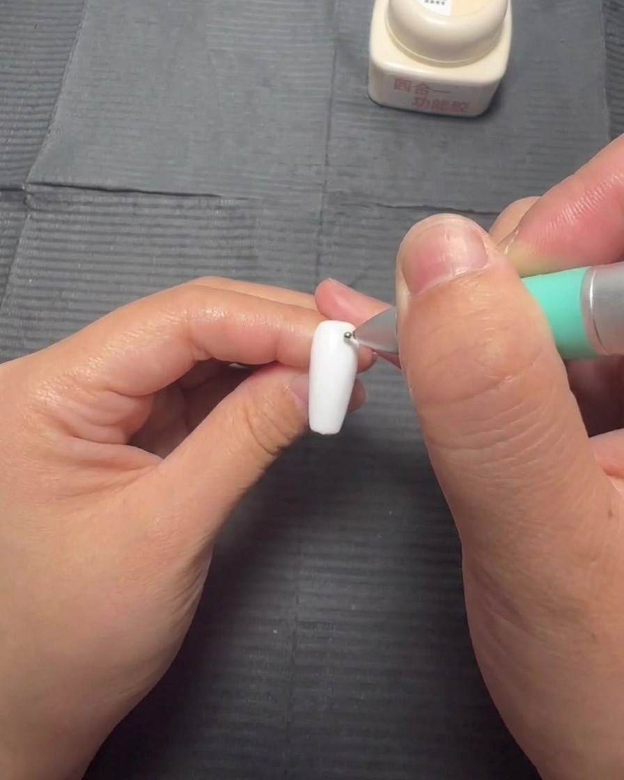Un pinceau de flacon appliquant une fine couche de gel blooming transparent sur un ongle blanc.