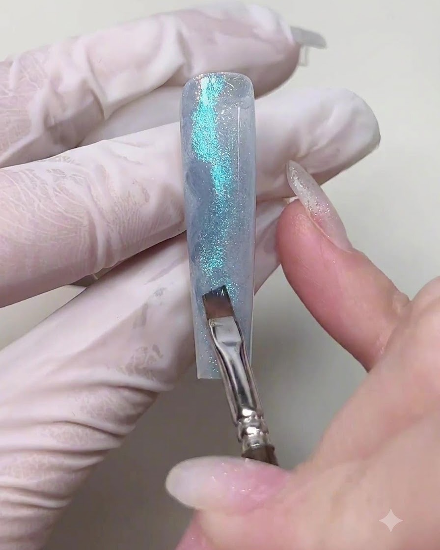 Un pinceau plat biseauté tapotant du gel bleu marine foncé dans les rainures latérales dun ongle en gel texturé pour créer des effets dombre.