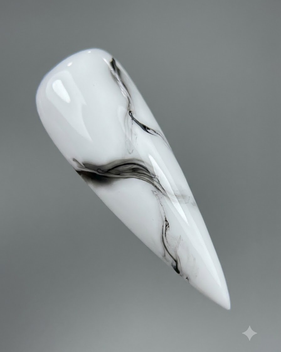 Vue rapprochée dun design de marbre noir et blanc en train de diffuser sur un ongle.