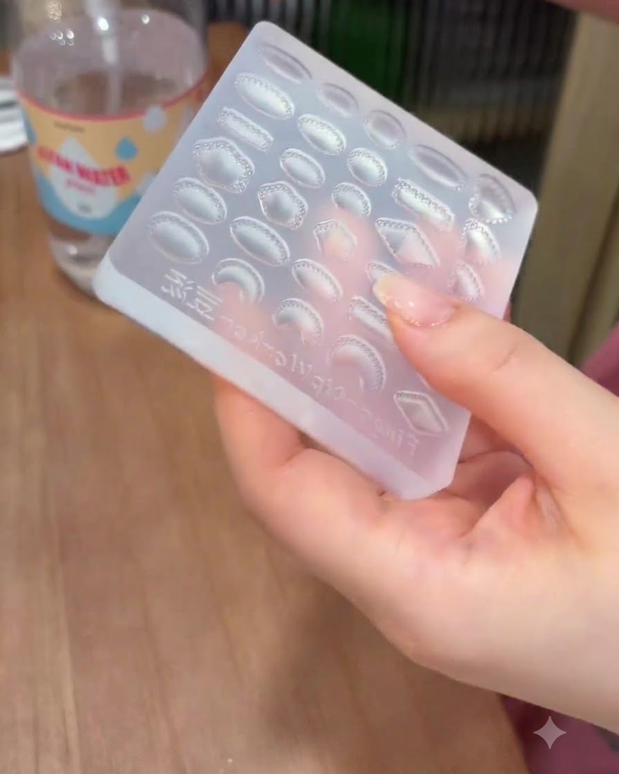 Une main tenant un moule en silicone transparent avec des cavités en forme de gemme tout en lessuyant avec une lingette nettoyante.