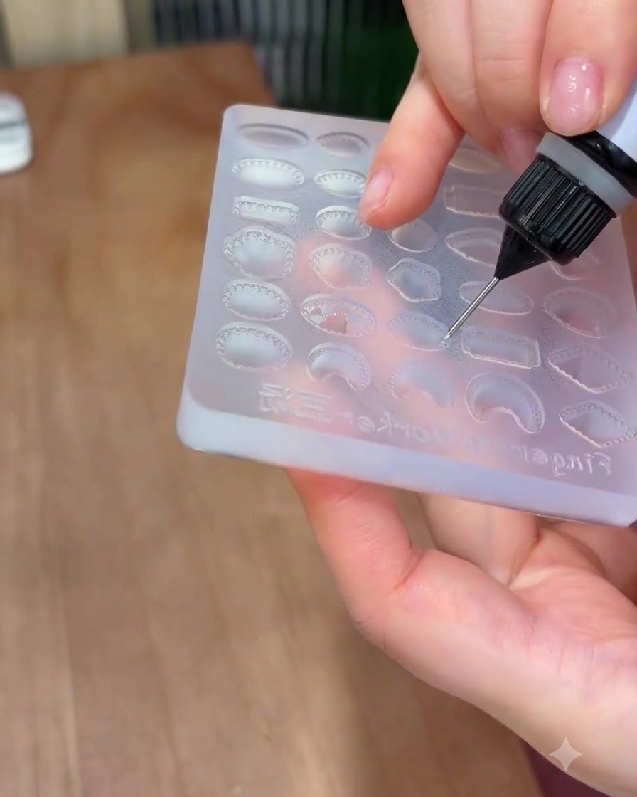 Un embout de précision remplissant une cavité de gemme ovale sur un moule en silicone avec du gel solide transparent.