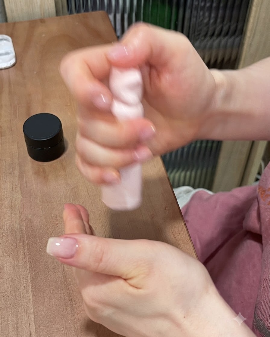 Une mini lampe UV/LED rose catalysant une pièce de gemme en gel cat-eye bleu montée sur un support métallique.