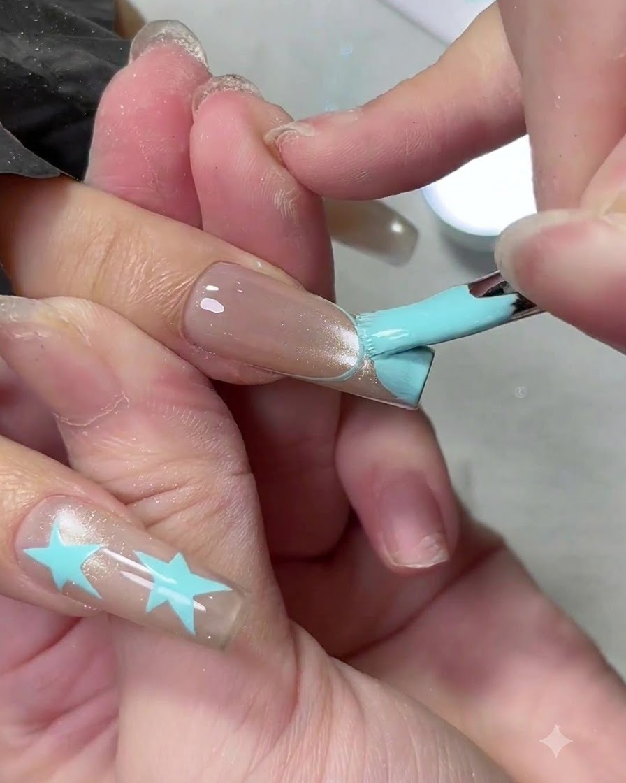 Un pinceau gel plat remplissant une pointe de French manucure bleu clair sur un long ongle.