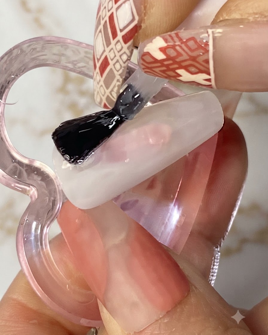 Pinceau à gel plat appliquant une couche de colle solide transparente sur un ongle blanc.
