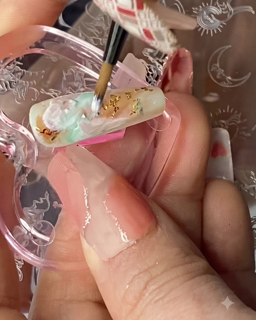 Pinceau fin de nail art dessinant de délicates lignes blanches semi-transparentes sur un fond estompé multicolore.