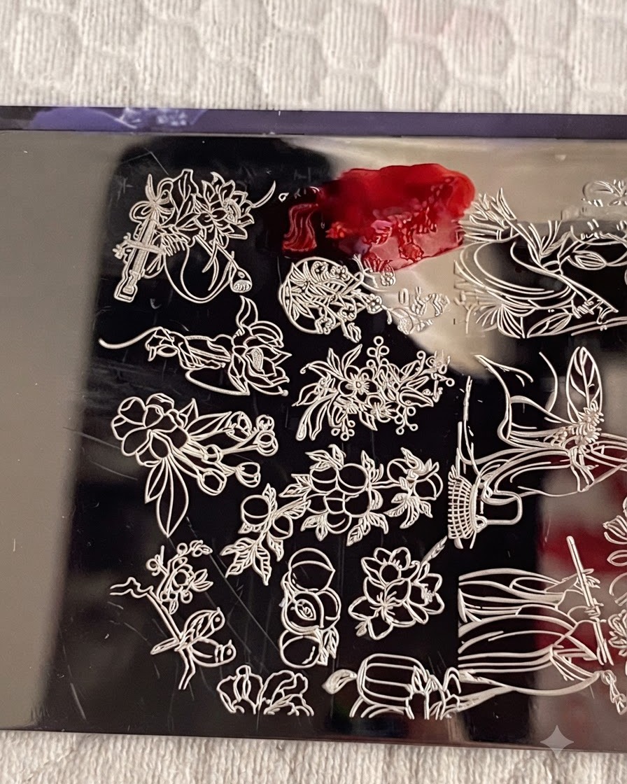 Une plaque destampage métallique avec le vernis destampage numéro 1 appliqué sur le motif de fleur, et une carte racloir enlevant lexcès de vernis.