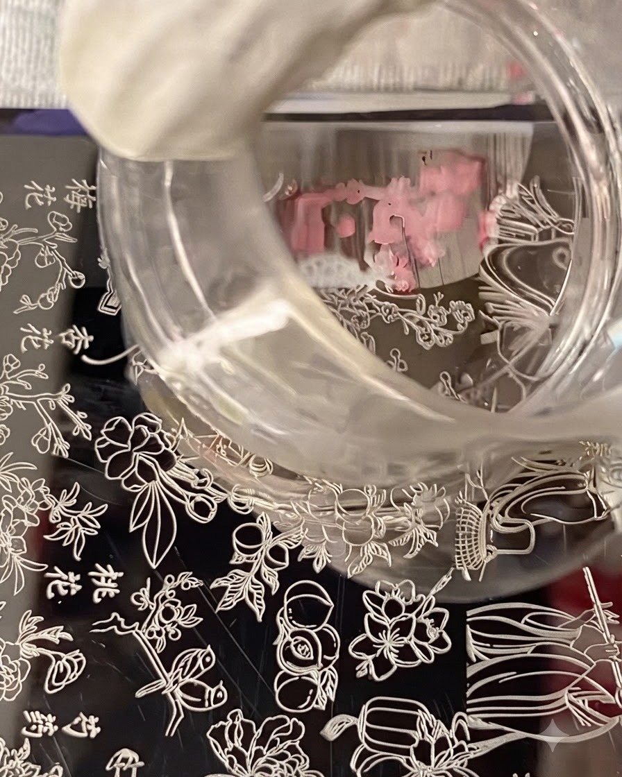 Un tampon en silicone transparent survolant une plaque destampage, capturant le design de nail art floral.