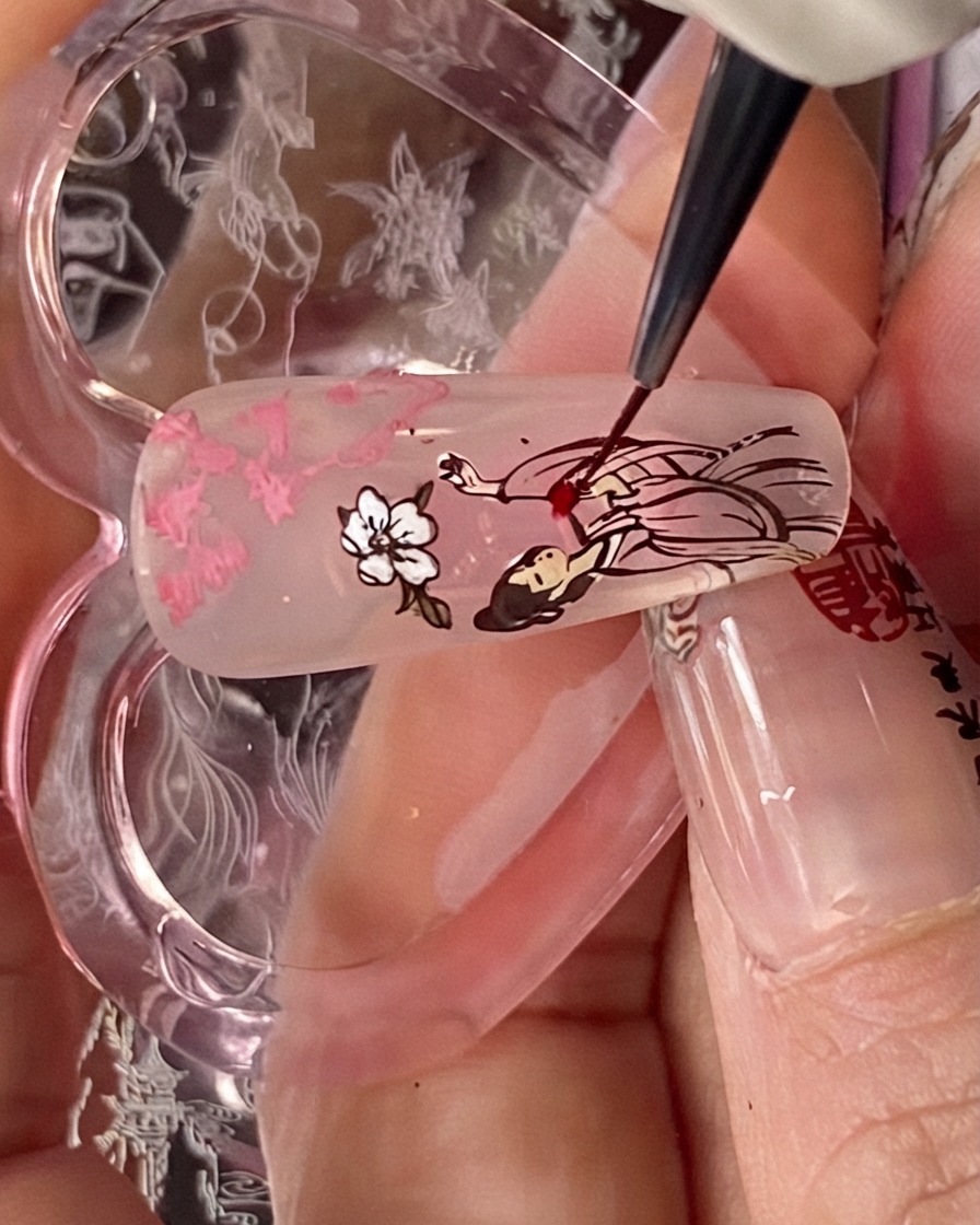 Un pinceau de détail appliquant du liquide blooming rouge sur la partie de la robe de la figure estampée sur une capsule dongle.