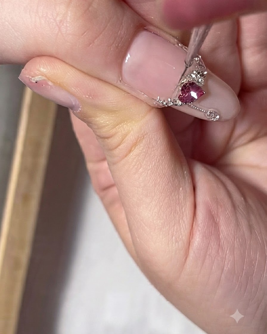 Gros plan dun ongle de pouce présentant un gemme ovale rouge disposé pour ressembler à un pendentif de collier.