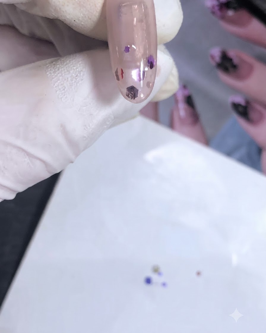 Gros plan dun ongle manucuré avec des sequins de première couche encapsulés en cours de catalysation sous une lampe UV/LED.