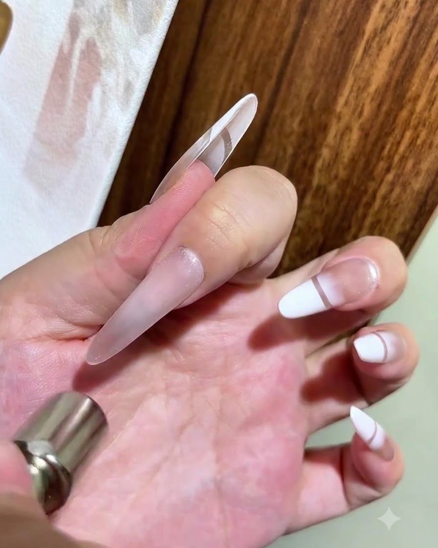 Une main tenant un aimant cylindrique au-dessus dun ongle en gel cat eye brillant pour former un effet perle de verre lumineux.