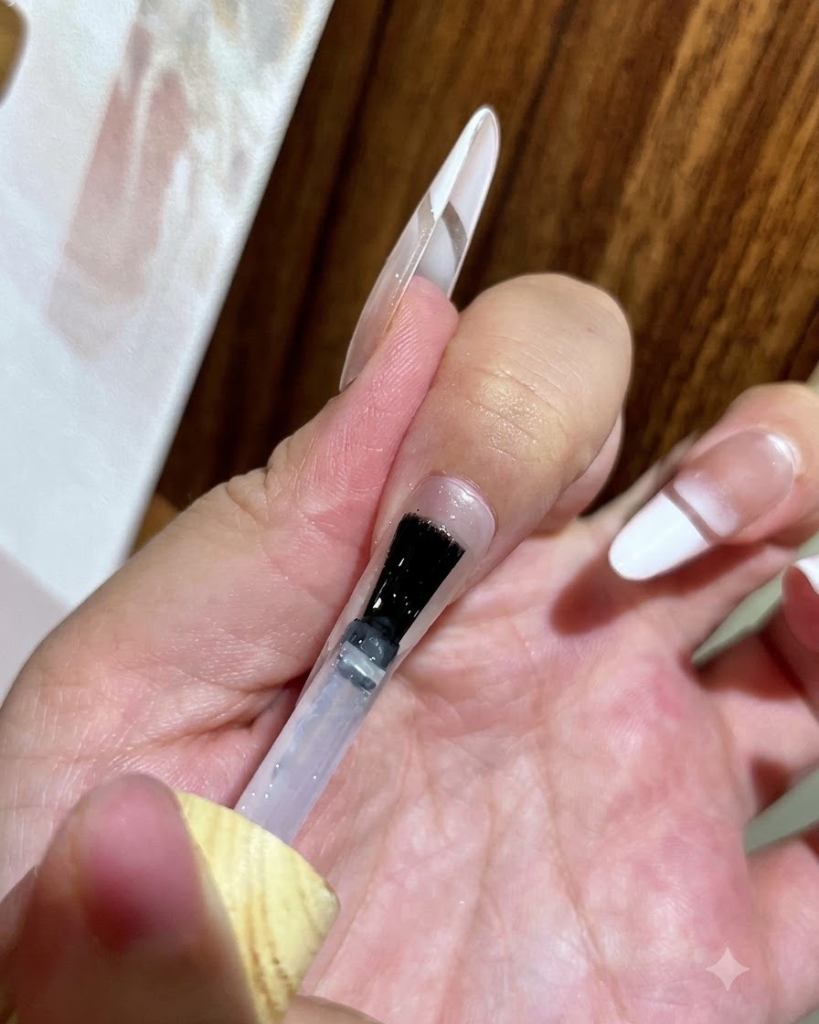 Un pinceau appliquant un top coat transparent et brillant sur un ongle décoré.