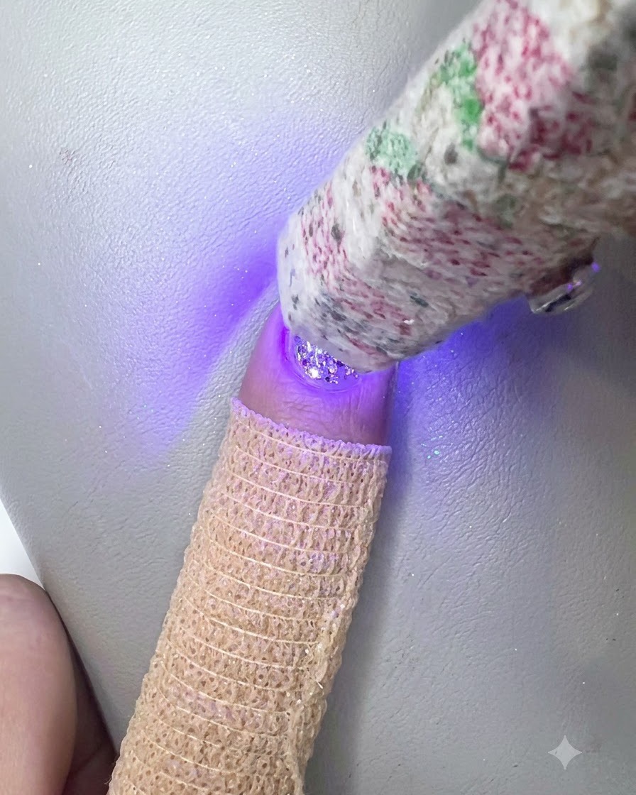 Une lampe UV LED portable catalysant la couche de gel de construction transparent sur longle à paillettes.