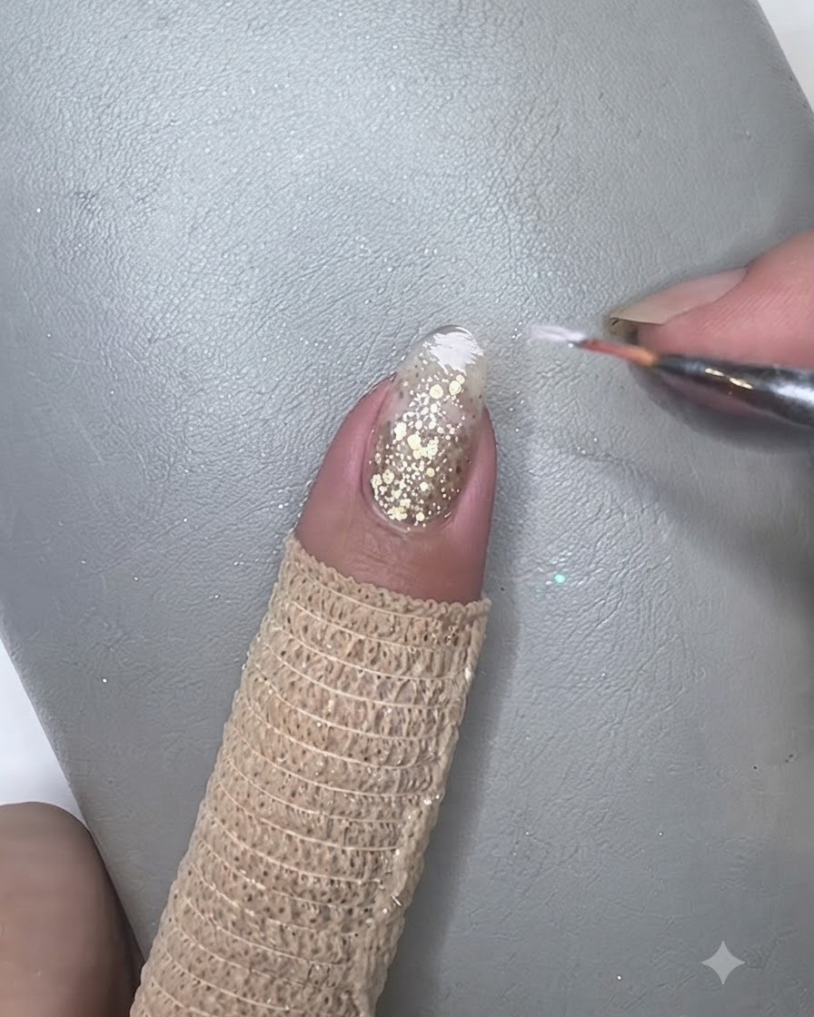 Un pinceau tapotant doucement du gel blanc ivoire sur le bout dun ongle manucuré pour former un effet de dégradé.