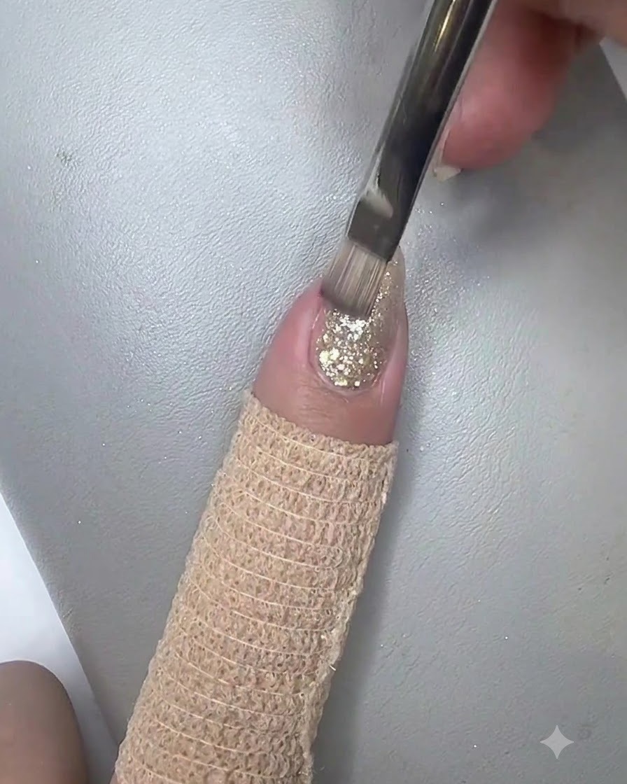 Un pinceau plat appliquant une couche scintillante de gel cat eye sur longle pré-décoré.