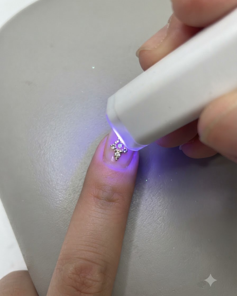 Une lampe UV LED miniature portable catalysant un ongle décoré sur un doigt.