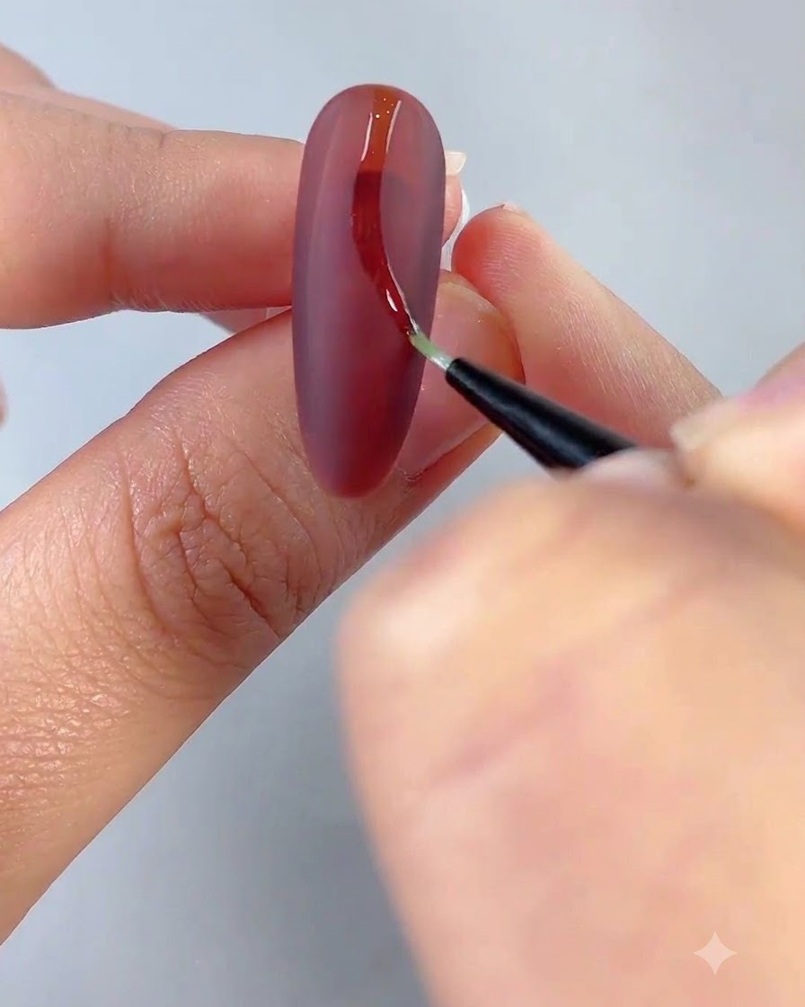 Un pinceau de détail fin dessinant une ligne incurvée claire sur une surface dongle rouge mat.