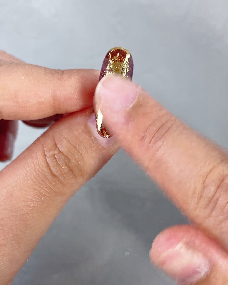 Un doigt frottant de la poudre métallique dorée sur les éléments décoratifs en relief dun ongle.