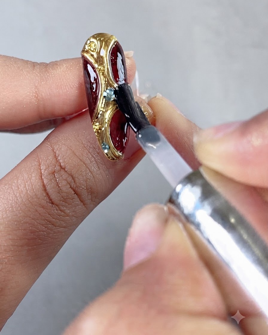 Un pinceau appliquant une couche de scellement finale de top coat brillant sur longle entièrement décoré.