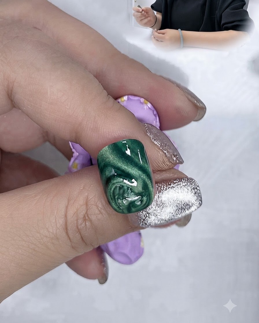 Un aimant cylindrique planant juste au-dessus de la surface dun ongle en gel cat-eye vert.